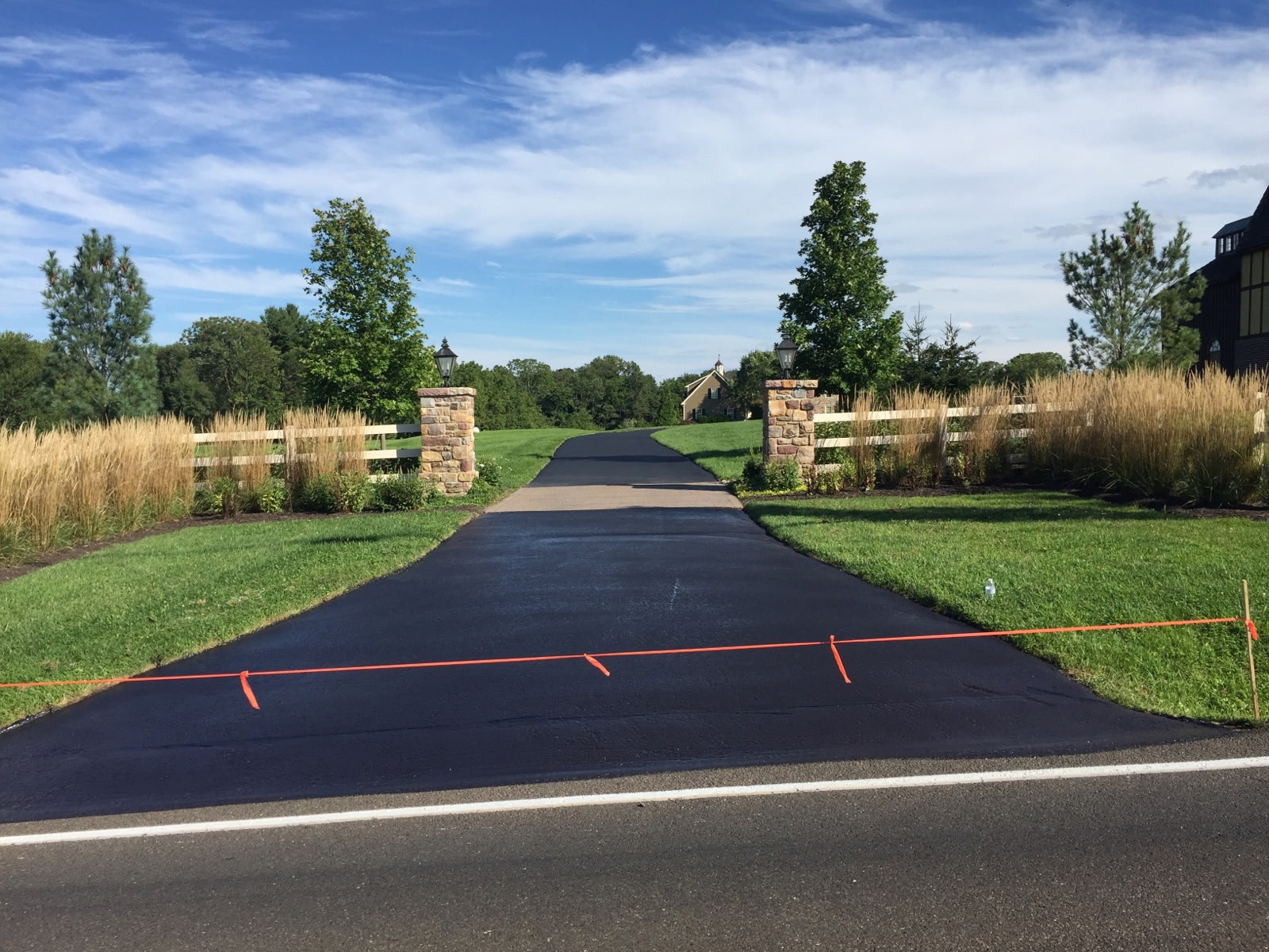 Long black driveway leading between stone gateposts