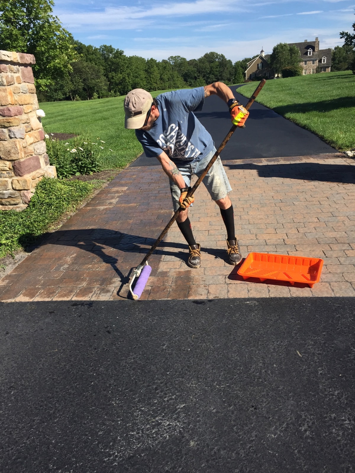 Driveway Concepts worker applying a finish to a paver entrance
