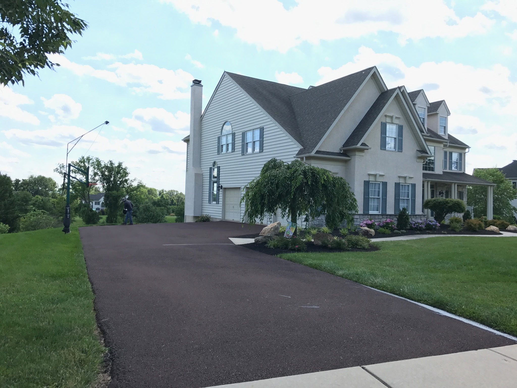 Dark asphalt driveway beside a light-colored house